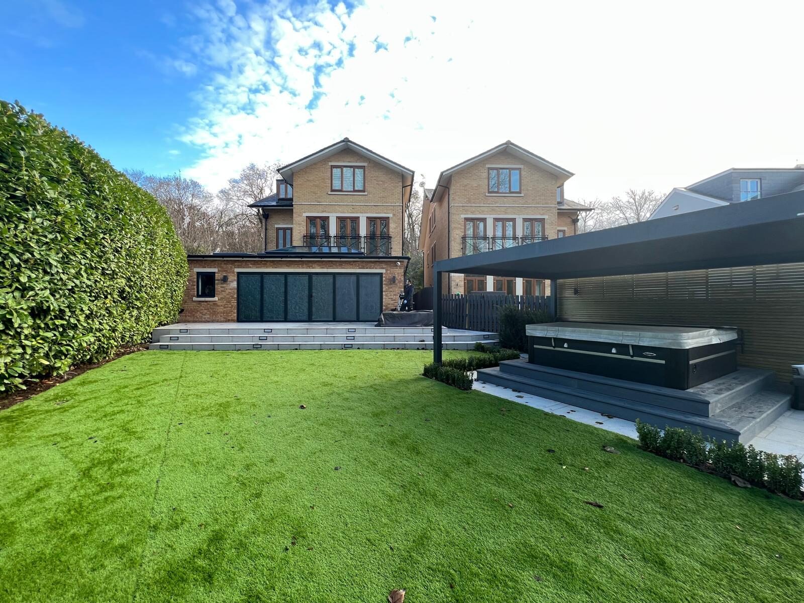 Garden room with dark bifolding doors opening onto a lawn and terrace